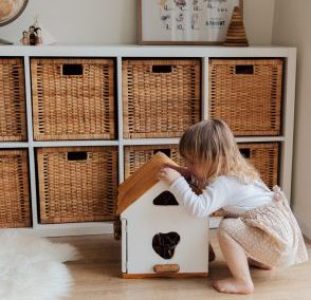 girl-playing-with-a-wooden-toy-house-3933028