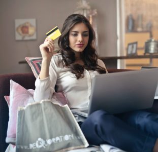 woman-holding-card-while-operating-silver-laptop-919436